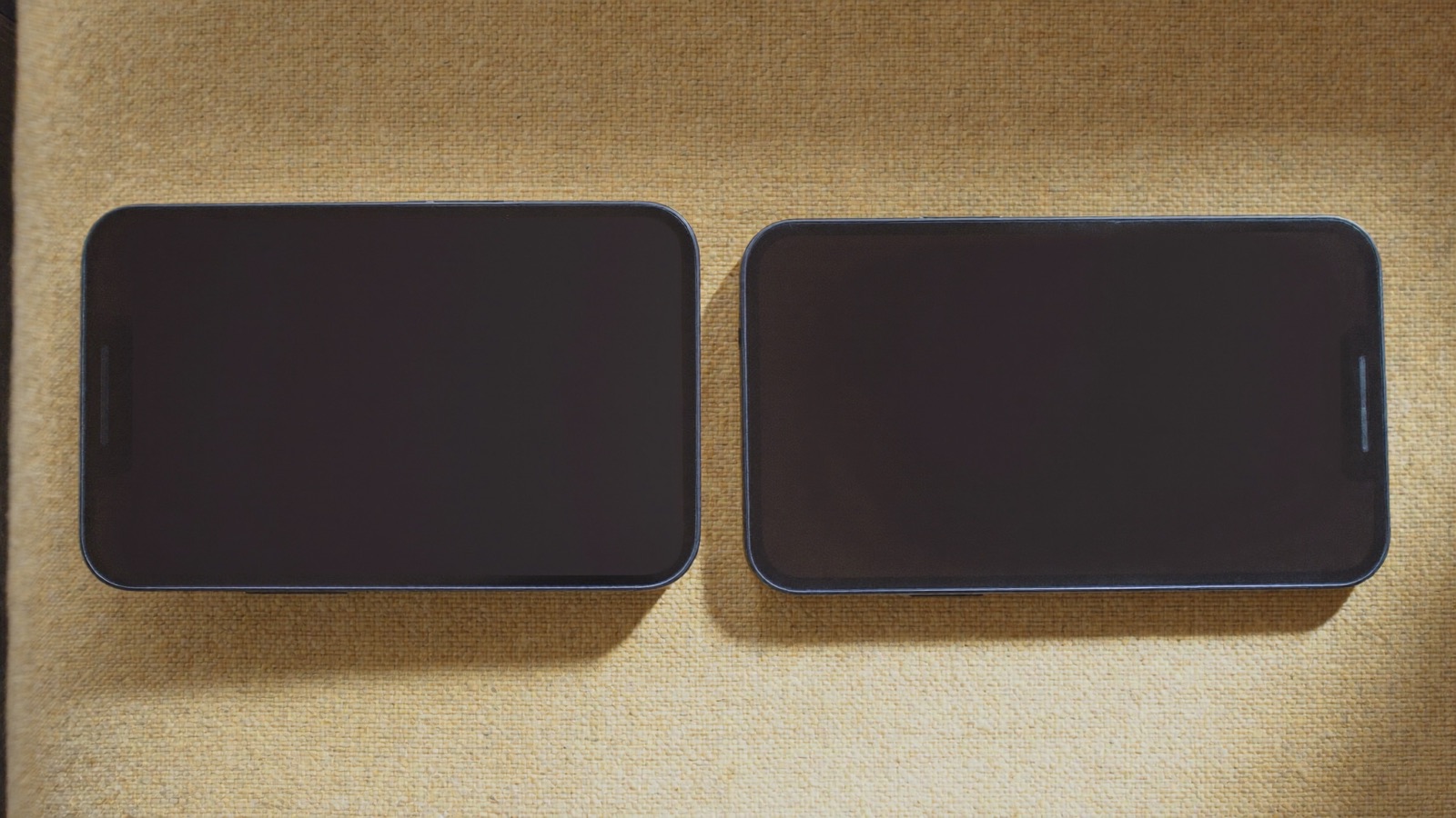 Deux smartphones côte à côte sur une surface en tissu beige, vus du dessus.